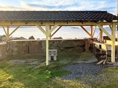 a wooden gazebo with a bench under it at 6 person holiday home in Aukra in Aukra