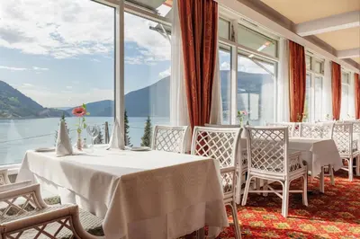 a restaurant with tables and chairs and a view of the water at Olden Fjordhotel in Olden