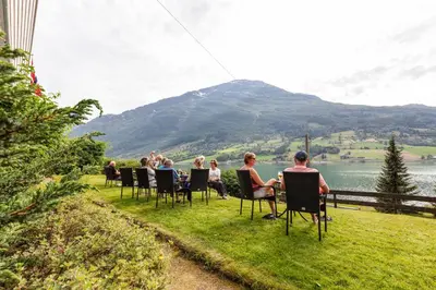 a group of people sitting in chairs on the grass at Olden Fjordhotel in Olden