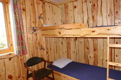 a bedroom with a bunk bed and a chair at Lunde Turiststasjon in Skei