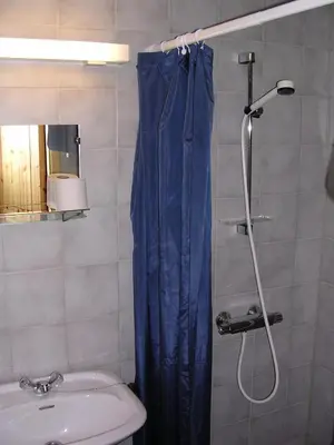 a shower with a blue shower curtain in a bathroom at Lunde Turiststasjon in Skei