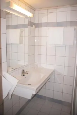 a white bathroom with a sink and a mirror at Midtnes Hotel in Balestrand