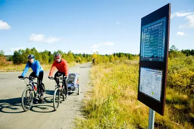 two people riding bikes on a road next to a sign at Oset Fjellhotell in Gol