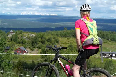 a woman standing next to a bike on a hill at Oset Fjellhotell in Gol