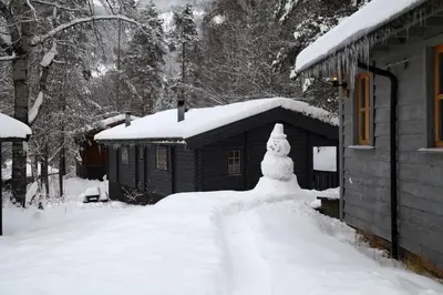 a snowman in front of a house in the snow at Vesterland Feriepark Hytter, hotell og leikeland in Sogndal