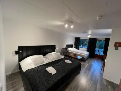 a bedroom with a bed with a black bedspread and white sheets at Vesterland Feriepark Hytter, hotell og leikeland in Sogndal