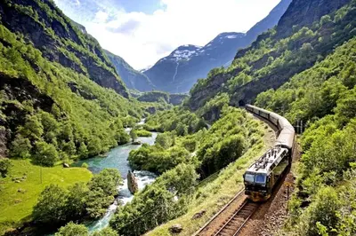 a train traveling down the tracks near a river at Hotel Aurlandsfjord in Aurland