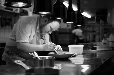 a man in a kitchen preparing food in a bowl at Hotel Aurlandsfjord in Aurland