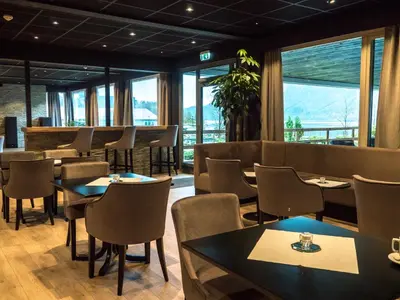 a restaurant with tables and chairs and windows at Bremanger Fjord Hotell in Svelgen
