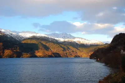 a lake with snow covered mountains in the background at Åkrafjordtunet Apartments in Teigland