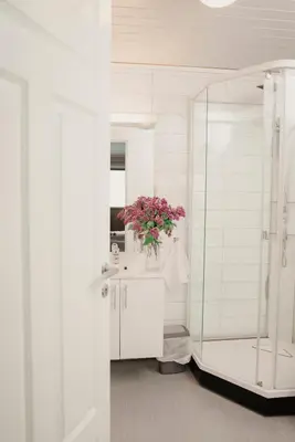 a white bathroom with a sink and a vase of flowers at Åkrafjordtunet Apartments in Teigland