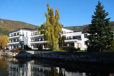 a building next to a body of water at Innvik Fjordhotell in Innvik