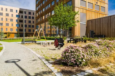 a park with a playground and a tree and flowers at Wood Hotel by Frich's in Brumunddalen