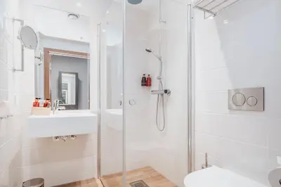 a white bathroom with a shower and a sink at Wood Hotel by Frich's in Brumunddalen