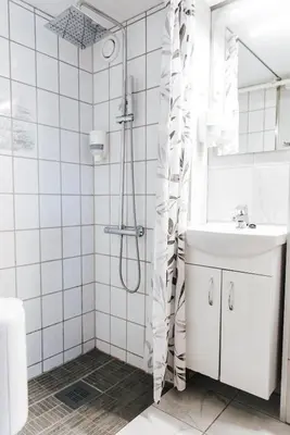 a white bathroom with a shower and a sink at Vågslidtun Hotel in Vågsli