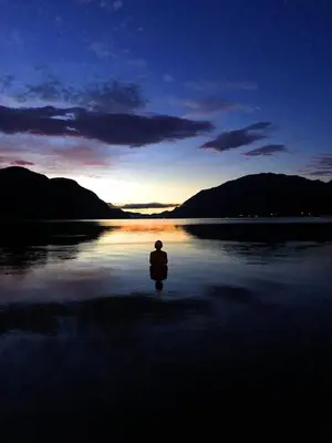 a person sitting on the shore of a body of water at Sandviken Camping in Austbygdi