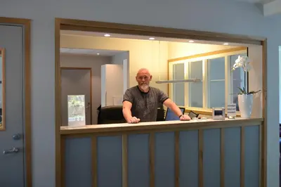 a man standing behind a counter in an office at Birkelunden Bed & Breakfast in Rjukan
