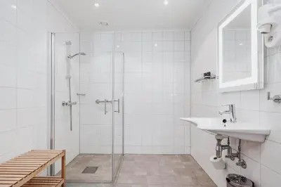 a white bathroom with a sink and a shower at Frich's Hotell og Spiseri Alvdal in Alvdal