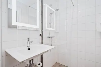 a white bathroom with a sink and a shower at Frich's Hotell og Spiseri Alvdal in Alvdal
