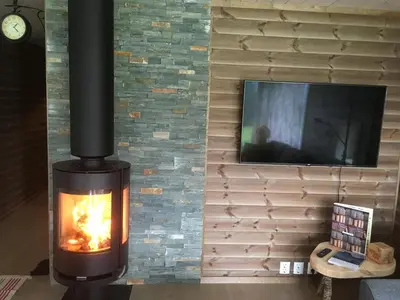 a fireplace with a tv on a brick wall at Heinåli Hytta in Isfjorden