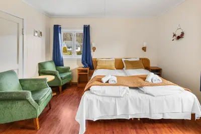 a bedroom with two beds and two green chairs at Hardanger Guesthouse in Ulvik