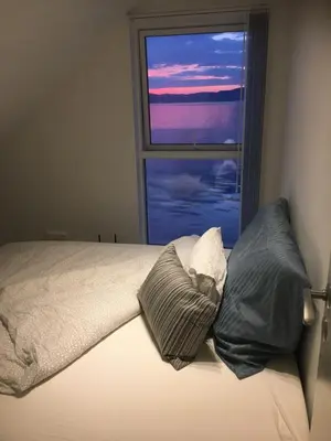 a bed with two pillows in front of a window at Seaside Rentals in Trondheim