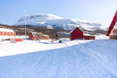 a snow covered road with a red barn and a mountain at Maristova apartment 109 in Filefjell
