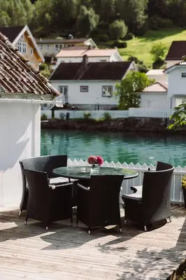 a patio with a table and chairs and water at Stryn - house by the river in Stryn