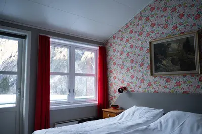 a bedroom with red curtains and a bed and two windows at Akrafjorden Nature B&B AS in Fjæra