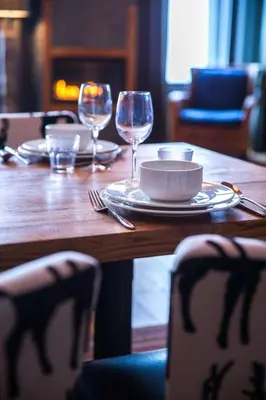 a wooden table with a plate and wine glasses at Skistar Lodge Trysil in Trysil