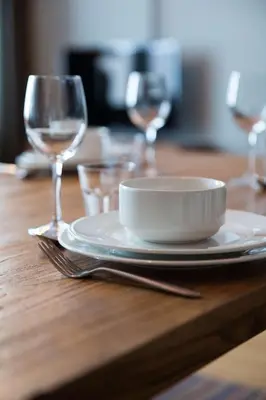 a wooden table with a plate and two wine glasses at Skistar Lodge Trysil in Trysil