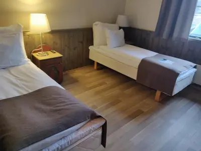 a room with two beds and a table with a lamp at Rondane Høyfjellshotell in Mysusæter