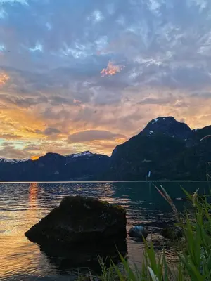 a large rock in the water with mountains in the background at Vollsnes Feriehus in Hjelle