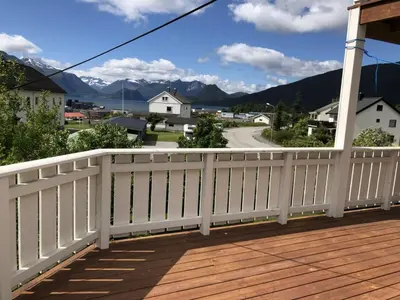 a white fence on a porch with mountains in the background at Åndalsnes gustehouse in Åndalsnes