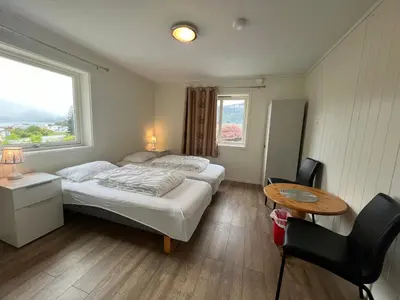 a bedroom with a bed and a table and a window at Åndalsnes gustehouse in Åndalsnes