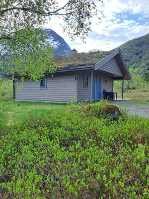 a small house with a mountain in the background at Stardalen Hyttegrend in Klakegg