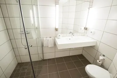 a bathroom with a sink and a toilet and a shower at Dolmsundet Hotell Hitra in Melandsjøen