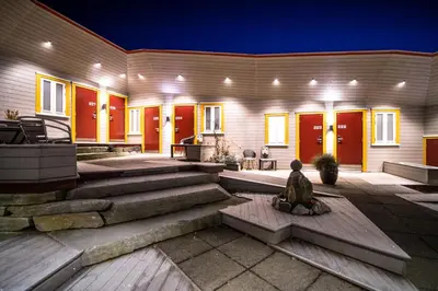 a house with red doors and a person sitting on the steps at Dolmsundet Hotell Hitra in Melandsjøen