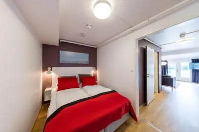 a bedroom with a red and white bed in a room at Dolmsundet Hotell Hitra in Melandsjøen