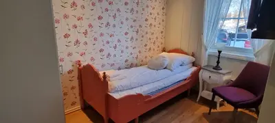 a small bed in a room with a flower wallpaper at Erzscheidergaarden Hotell in Røros