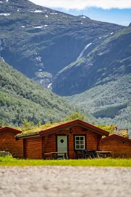 a log cabin with mountains in the background at Trollstigen Camping and Gjestegård in Åndalsnes