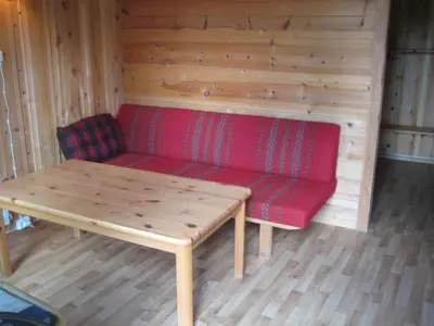 a red couch in a wooden room with a table at Jotunheimen Feriesenter in Heidal