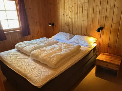 an unmade bed in a wooden bedroom with a window at Jotunheimen Feriesenter in Heidal