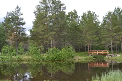 a wooden bench sitting next to a body of water at Jotunheimen Feriesenter in Heidal