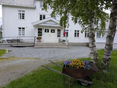 a wheelbarrow filled with flowers in front of a building at Granum Gård in Fluberg