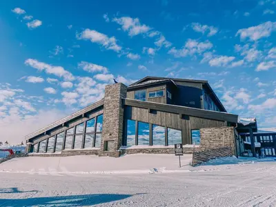 a building in the snow with a blue sky at Pellestova Hotell Hafjell in Hafjell