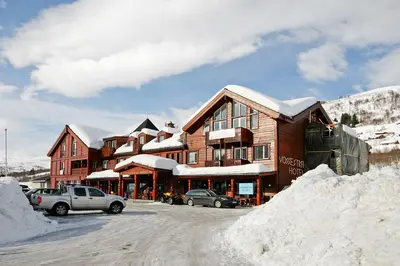 a snow covered building with cars parked in a parking lot at Vossestrand Hotel and Apartments in Myrkdalen