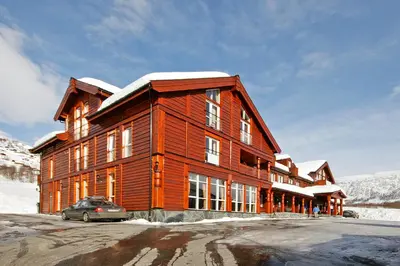 a large wooden building with a car parked in front at Vossestrand Hotel and Apartments in Myrkdalen