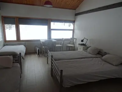 a bedroom with two beds and a table and chairs at Gjesteheim Havdal in Sundset