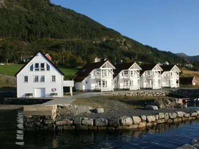 a row of white houses next to a body of water at 6 person holiday home in Åram-By Traum in Sandvik